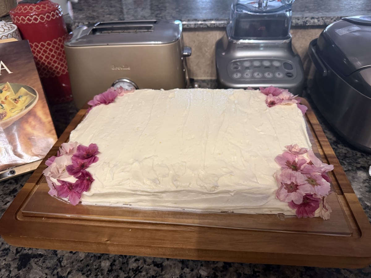 White sheet cake decorated with fresh pink flowers